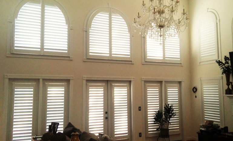 Television room in two-story Destin house with plantation shutters on tall windows.