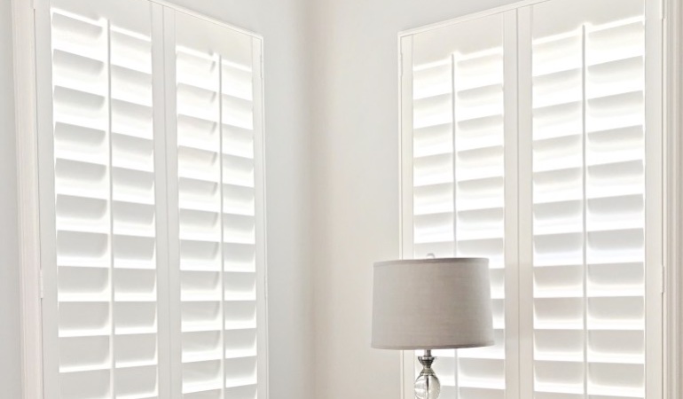Plantation shutters are available in a wide array of neutral whites and wood stains. Plantation shutters in a corner window.