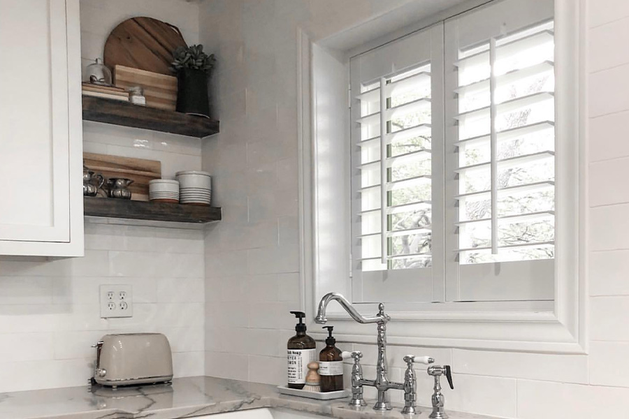 White and sleek kitchen with Polywood shutters above a kitchen sink.