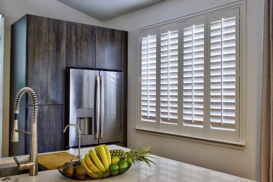 Homeowners use indoor window shutters in Destin when they want attractive and functional window treatments. Polywood shutters on a large kitchen window