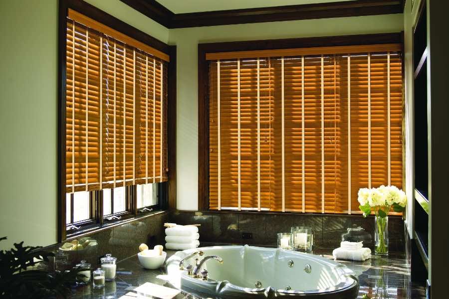 Premium quality blinds are always a stylish accent in your Destin home. Brown wood blinds on large windows in a green bathroom