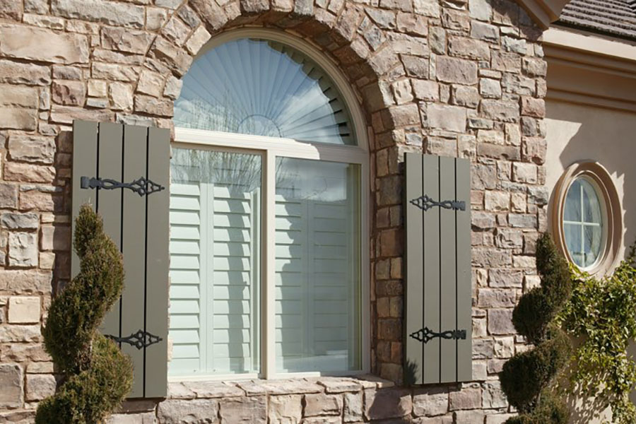 Interior shutters block annoying outside noise and give your home more curb appeal.  Exterior view of white Polywood shutters on a front window