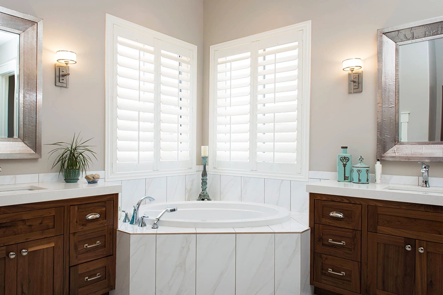 Durable Polywood shutters last many years, even on humid bathroom windows. White Polywood shutters on corner windows over a bath tub