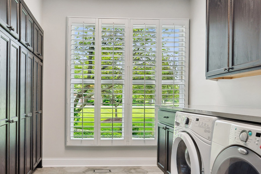 Find the perfect level of natural light for your Destin laundry room with interior shutters. White Polywood shutters letting light through a laundry room window