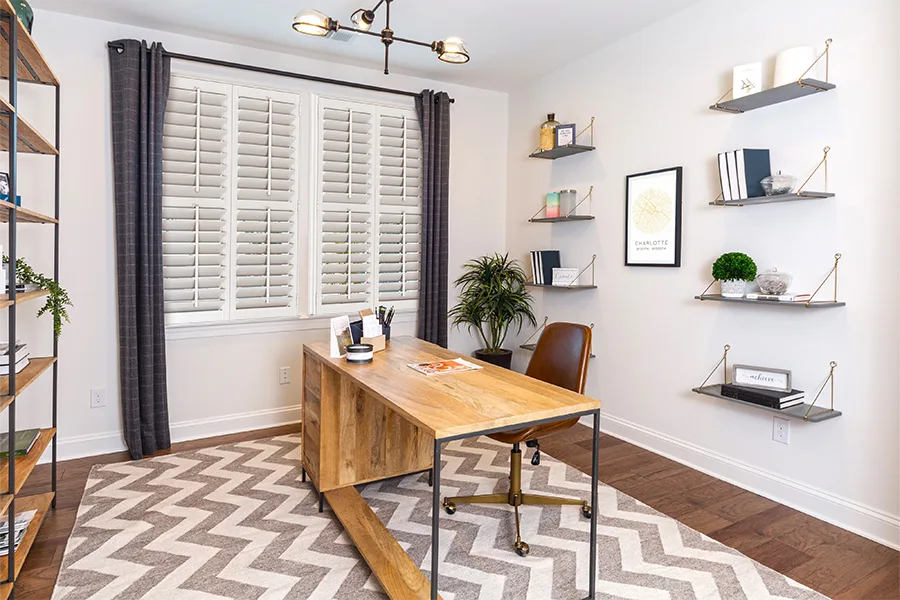 Dark gray drapes on a window with white Polywood shutters in a white home office
